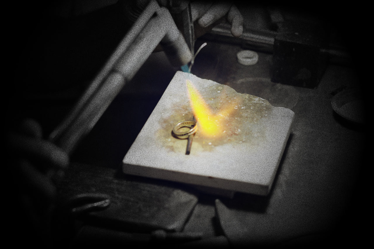 Jeweler soldering a silver ring with a precision torch